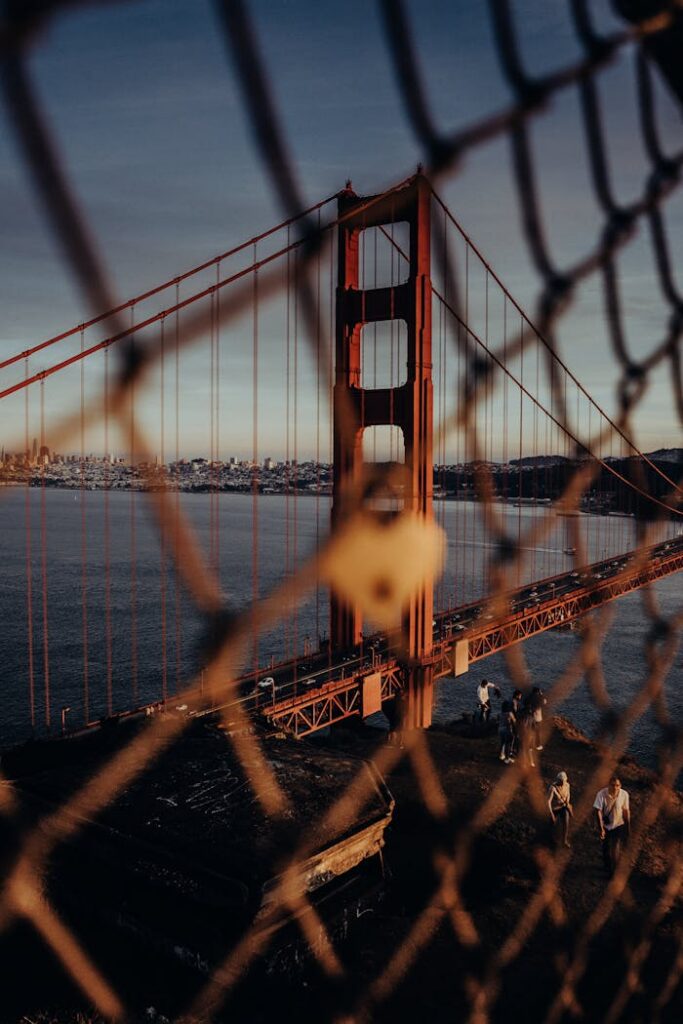Golden Gate Bridge through a fence during sunset, adding a unique frame to the iconic San Francisco landmark.